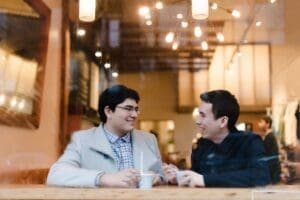 Two men sitting at a table talking to each other.